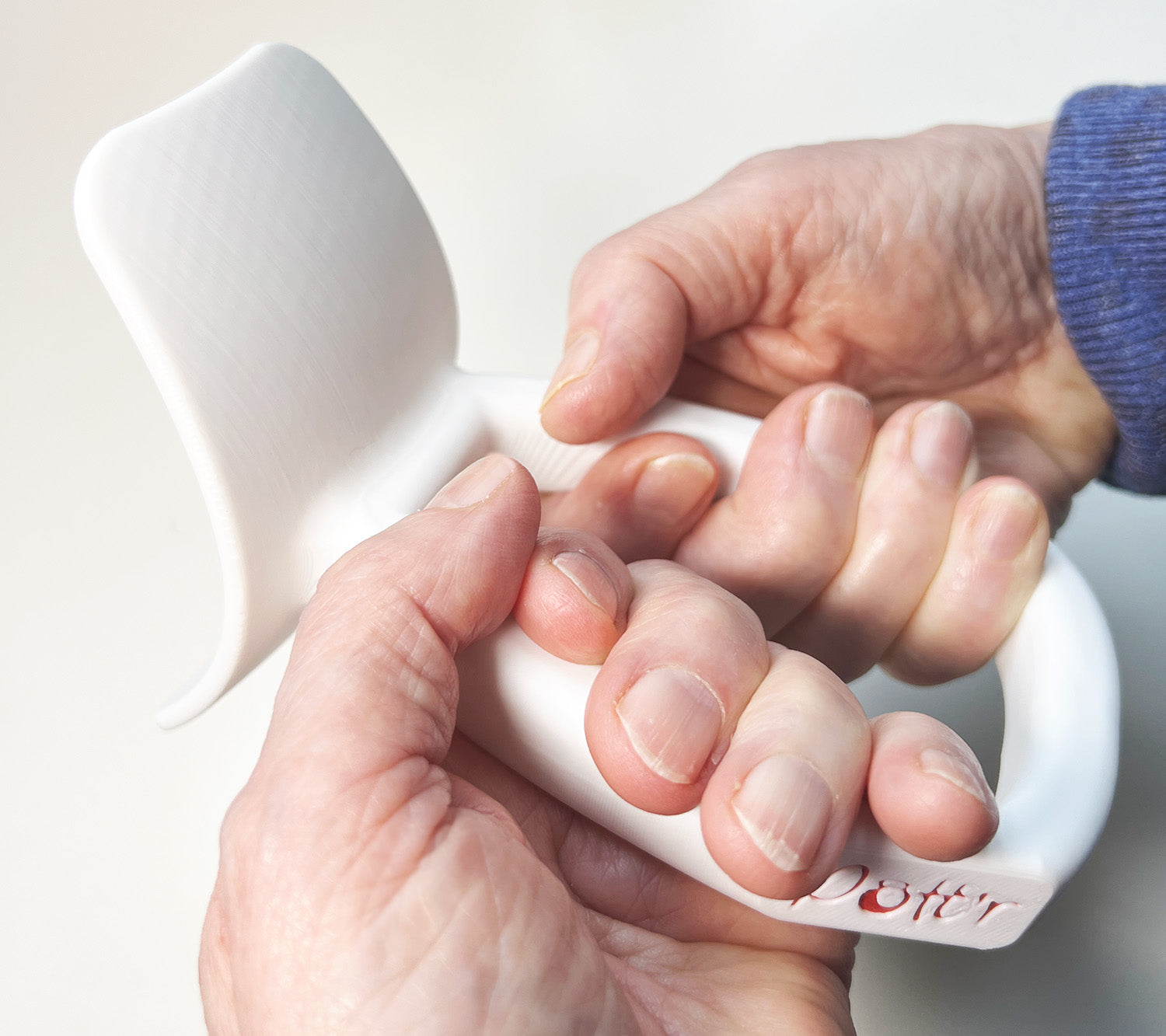 Close-up of a hand holding a pottery tool for shaping and crafting clay, showing detailed grip and tool design