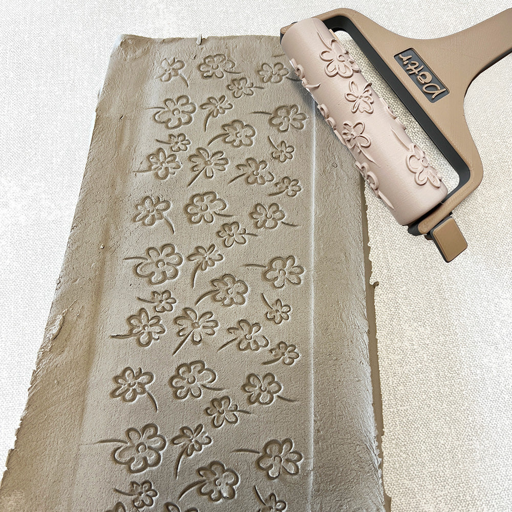 Detailed view of a 90mm flower line repeat roller with carved flower designs for use in ceramic artwork.