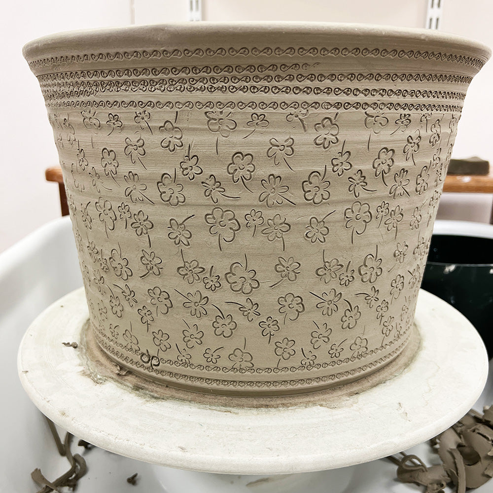 Side view of a 90mm flower line repeat roller displaying a continuous floral pattern for pottery decoration.